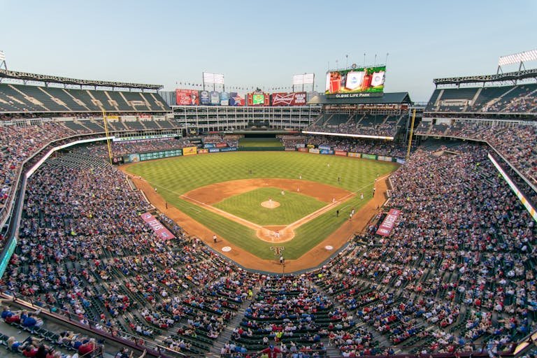 Aerial view of a lively baseball game at the iconic Globe Life Park filled with cheering fans.