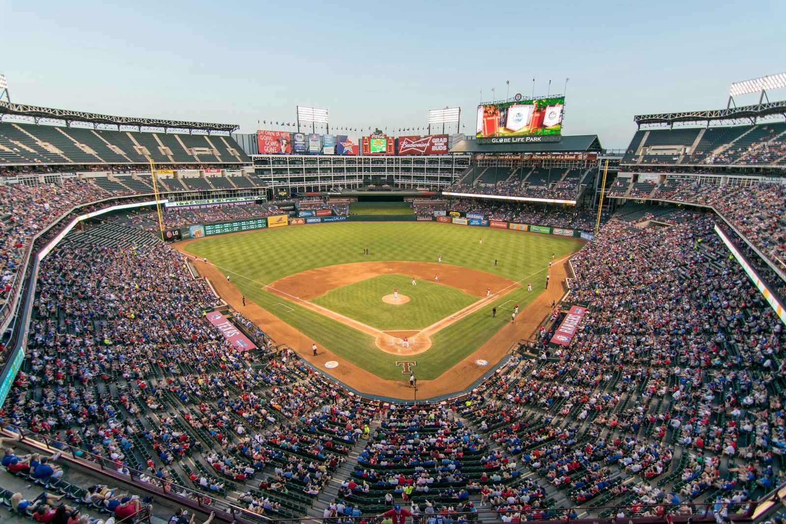 Aerial view of a lively baseball game at the iconic Globe Life Park filled with cheering fans.